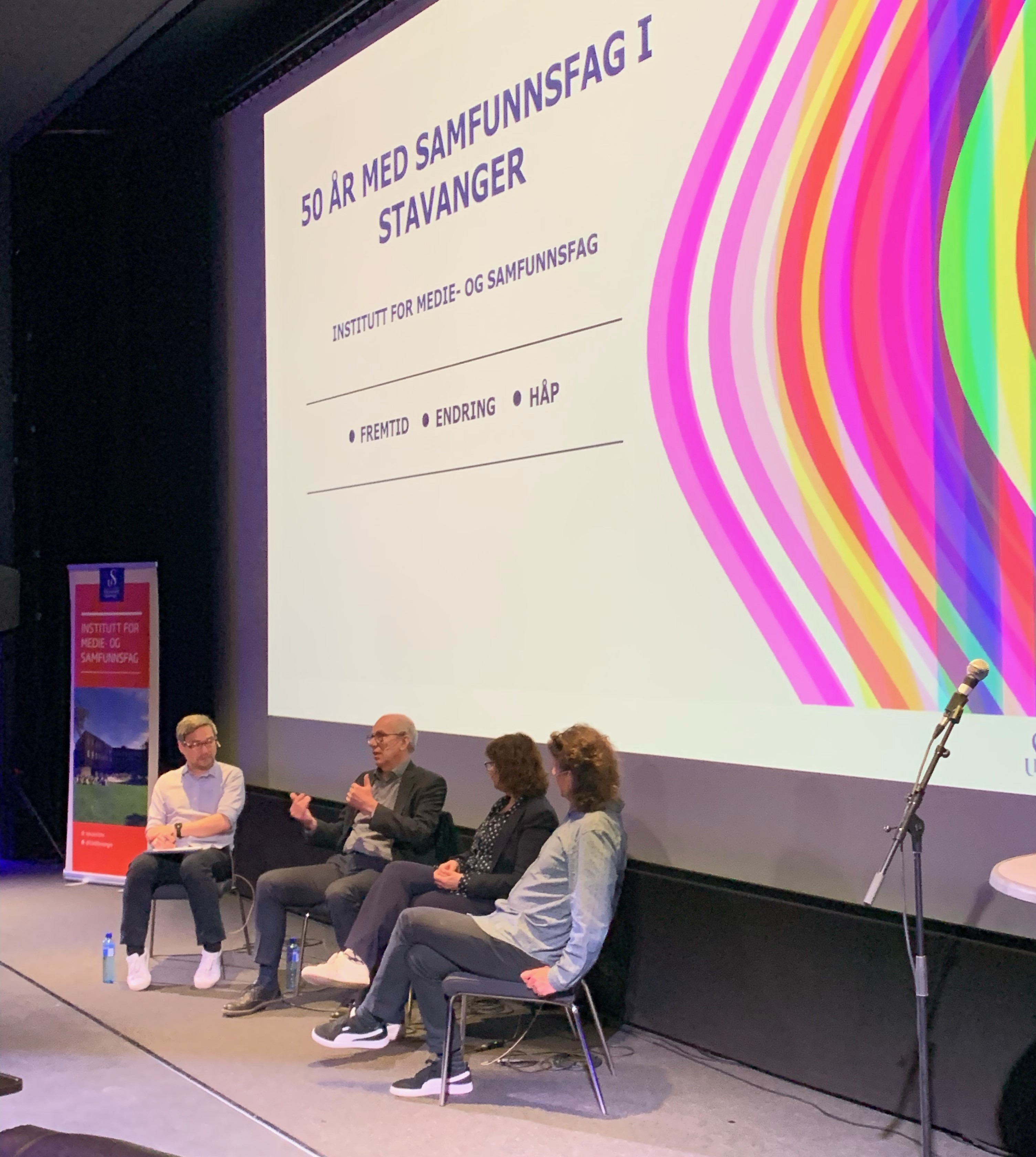 Anders Riel Muller, Peter Maassen, Turid Borgen og Tomas Sundnes Drønen sitter på en scene under en debatt. 