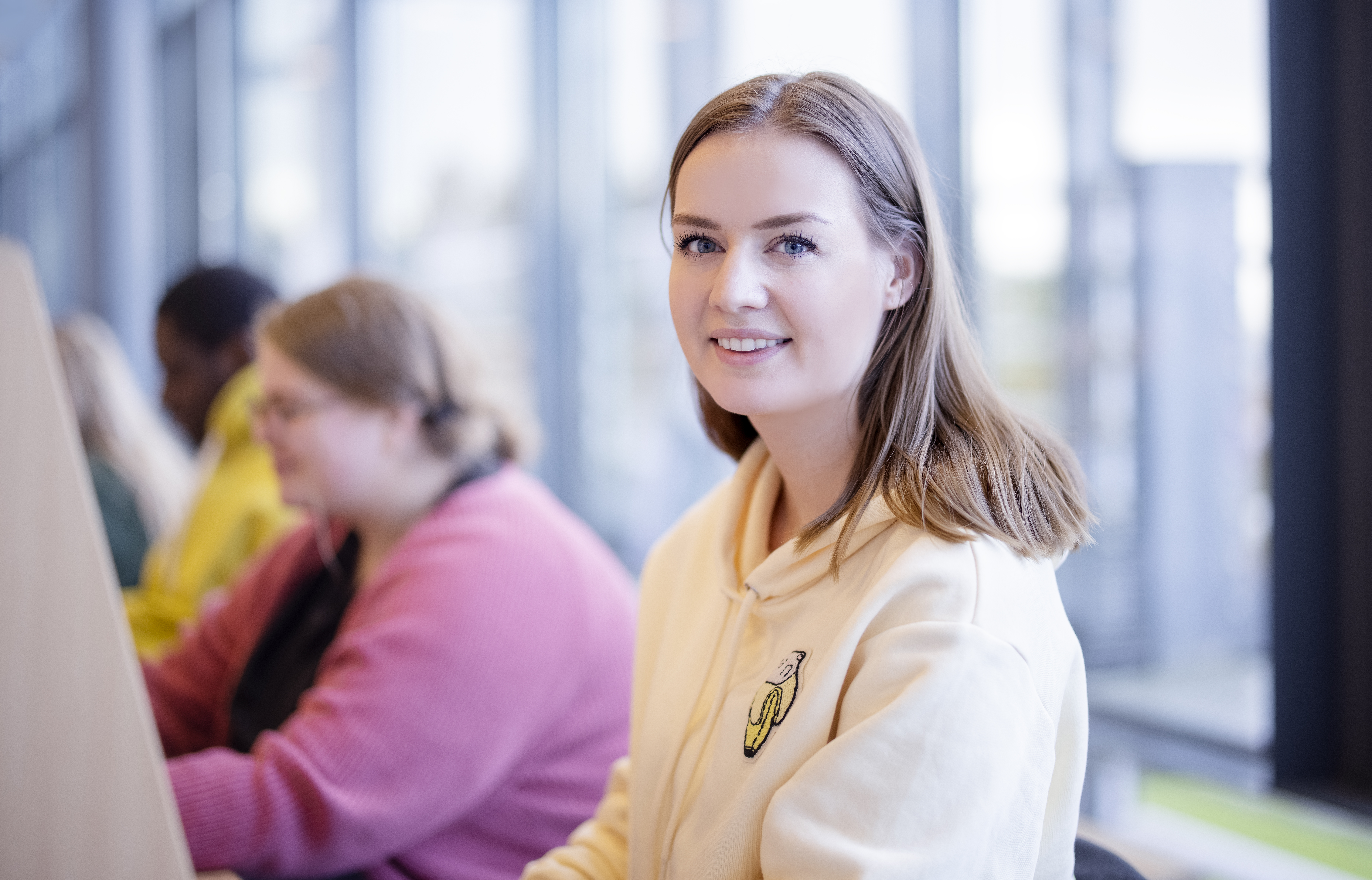 Kvinnelig student på lesesal smiler til kameraet