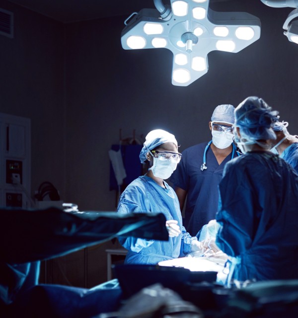 Tre helsearbeidarar ved operasjonsbordet.
