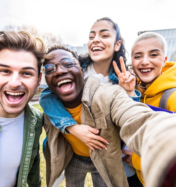 Fire studenter smiler og tar selfie