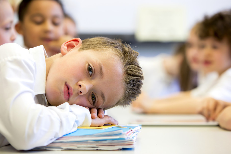 Trist gutt hviler holdet på pulten. Foto: iStock.