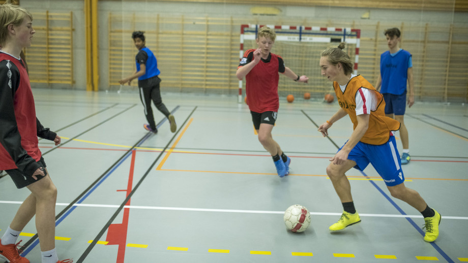 Fem gutter spiller fotball i en gymsal