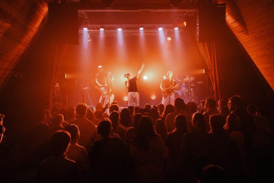 Et band står på en scene med mange publikummere foran