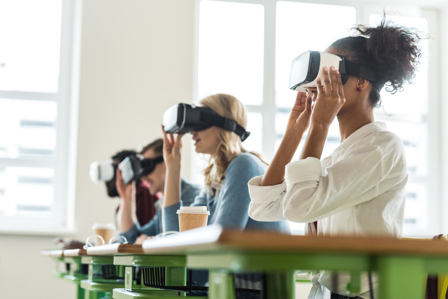 Fire personer sitter i et klasserom med VR-briller på.